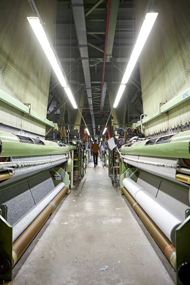 man walking between looms in factory
